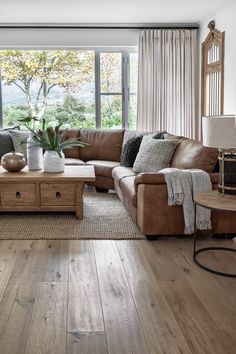 a living room filled with furniture and a large window covered in curtains next to a wooden floor