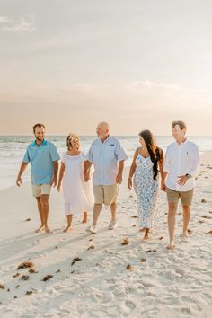 a family walking on the beach at sunset