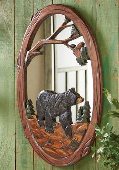 a mirror with a bear and bird in it on a wooden wall next to a potted plant