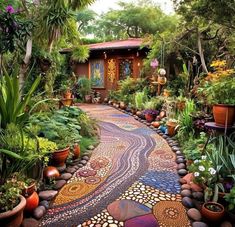 an outdoor garden with lots of plants and rocks on the path leading to a house