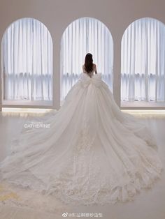 a woman in a white wedding dress is looking out the window with her back to the camera