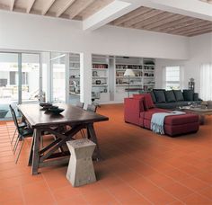 a living room filled with furniture next to a dining table and bookshelf on the wall