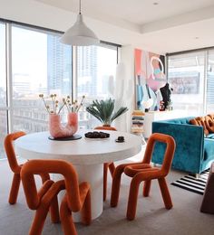 a living room filled with furniture and a table in front of large windows next to a blue couch