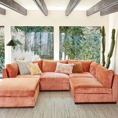 an orange sectional couch in front of a large window with cactus plants on the side