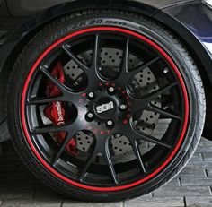 the front wheel of a sports car with red and black rims