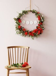 a wooden chair sitting next to a wall with a wreath on it