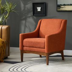 an orange chair sitting in a living room next to a potted plant on a rug