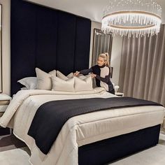 a woman sitting on top of a bed next to a chandelier in a bedroom