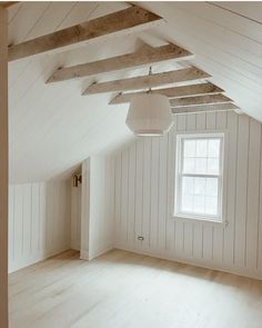 an empty room with white walls and wooden beams