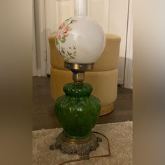 a green vase sitting on top of a table next to a lamp