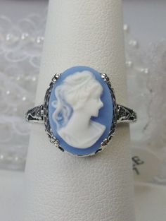 Cameo Ring Edward Design#70 Custom Made Here we have an Edwardian reproduction ring in sterling silver filigree with a variety of resin cameo options, choose from a black, light blue, or light pink lady silhouette, or an deep-orange daisy flower, or a light blue Bell flower. These beautiful cameos measure 14mm in length and 10mm in width. This ring also sits 7mm off the finger. The inside of the band is marked 925 for solid sterling. Notice the beautiful leaf and floral design of the filigree se Vintage Silver Ring With Intaglio, Vintage Silver Intaglio Rings, Vintage Sterling Silver Intaglio Ring, Fine Jewelry Silver Intaglio Rings, Fine Jewelry Silver Rings With Intaglio, Wedding Intaglio Jewelry Ring, Intaglio Wedding Ring Jewelry, Intaglio Ring For Wedding, Intaglio Wedding Ring