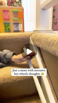 a child is playing on the stairs with a remote control in their hand and text reads, just a mom with intrusive hot wheels thoughs