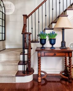 a wooden table with two vases on top of it next to a stair case