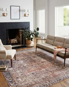 a living room filled with furniture and a fire place next to a large rug on top of a hard wood floor