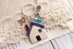 a house shaped keychain sitting on top of a piece of fabric next to flowers