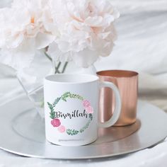 two coffee mugs sitting on a plate with flowers in the middle and behind them