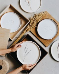 three plates with designs on them are being held by someone's hands and placed in boxes