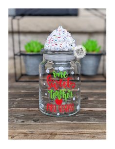 a glass jar filled with white frosting and sprinkles on top of a wooden table