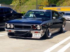 a black car parked in a parking lot next to other cars on the side of the road