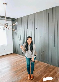 a woman is standing in an empty room with her hand up to the ceiling and holding a light bulb