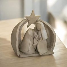 a ceramic nativity figurine sitting on top of a wooden table next to a star