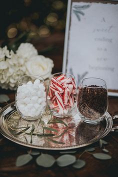 there are candy and marshmallows on the silver tray next to each other