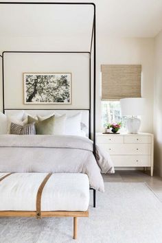 a bedroom with a canopy bed, white walls and carpeted flooring is shown