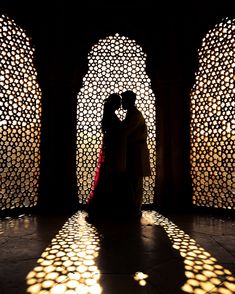 the silhouette of two people in front of an intricately designed wall and archways