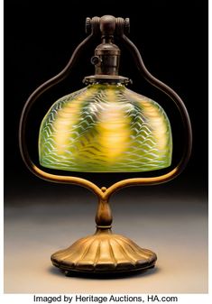 an old fashioned lamp with a green and yellow glass shade