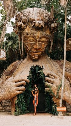 a woman standing in front of a giant wooden statue