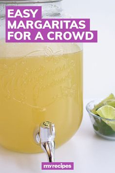 a mason jar filled with lemonade and limes next to a bowl of sliced limes