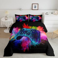 a bed covered in a black comforter with a colorful video game controller on it