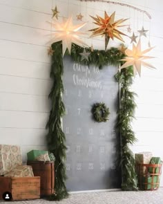 a chalk board with christmas wreaths and stars hanging from it's sides next to presents