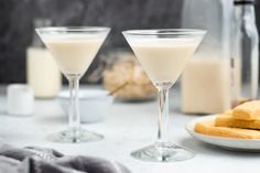 two glasses filled with white liquid next to some bread