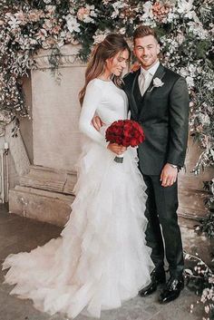 a bride and groom standing in front of a floral arch