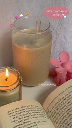 an open book next to a candle on a table