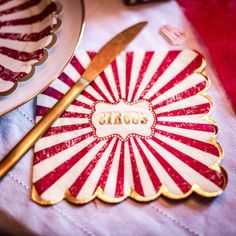 red and white striped napkins with the word circus on them next to a knife