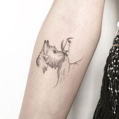 a woman's arm with a small tattoo of a dog on the left forearm