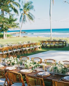 a long table set up with plates and place settings for an outdoor dinner on the beach