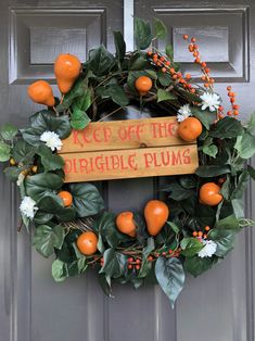 an orange wreath on the front door of a house with sign saying keep off the organic plums