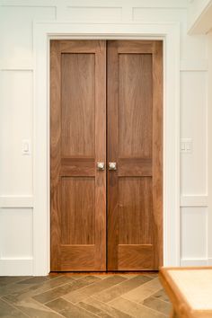 two wooden doors sitting in the middle of a room with white walls and wood flooring