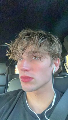 a young man with headphones in his ears sitting in the back seat of a car