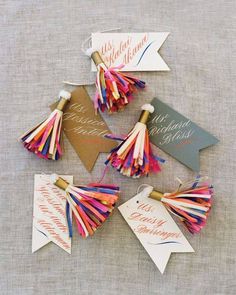 colorful paper tassels are arranged on top of each other, with tags attached to them