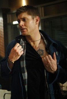 a man with a tattoo on his chest is holding something in one hand and looking at the other