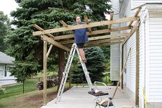 a man is standing on a ladder and working on a house roof that's being built