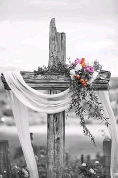 an old wooden cross with flowers on it