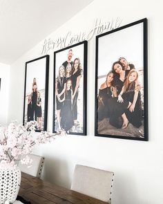 three framed photos hang on the wall above a dining room table with flowers in a vase