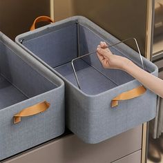 two blue storage bins with handles are held by a woman's hand in an office setting