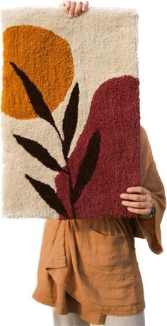 a woman holding up a rug with flowers on it