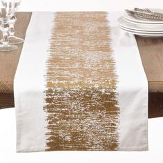 a white and gold table runner on top of a wooden table with silverware in front of it